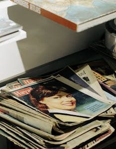A nostalgic stack of vintage magazines featuring classic covers and a world atlas.